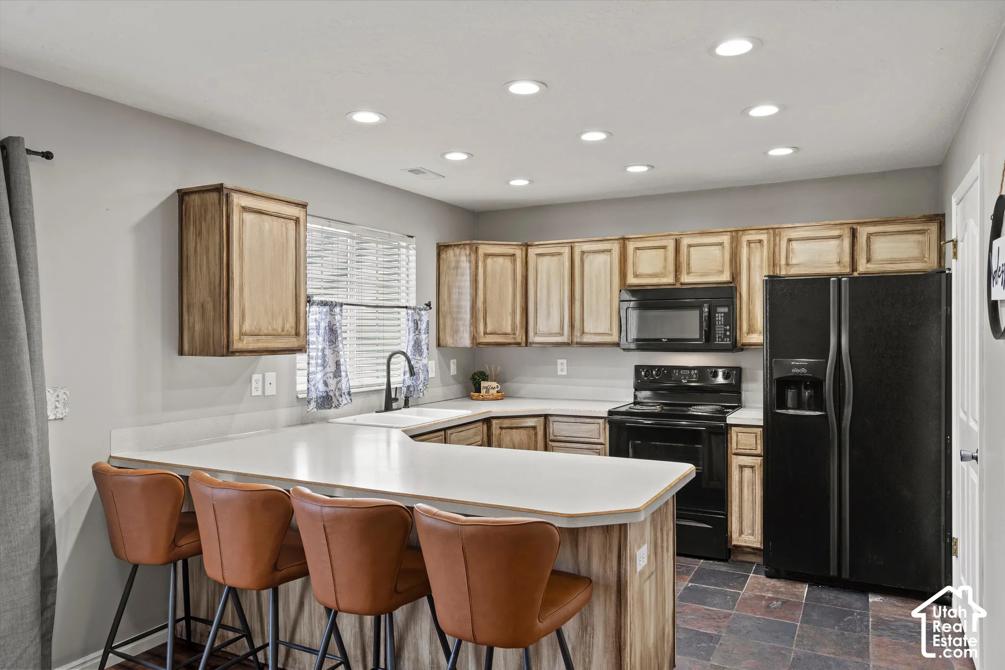 U-shaped kitchen with wood-finish cabinetry, light-toned countertops, and integrated recessed lighting
