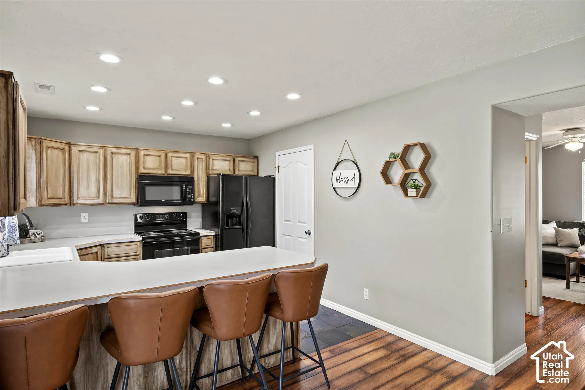 Kitchen featuring a white countertop with a sink, wood-finish cabinetry, recessed lighting, and black appliances