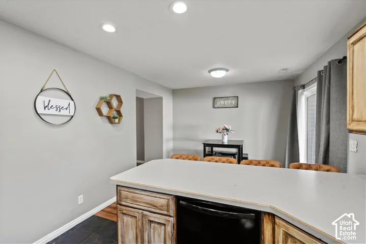 Kitchen featuring a built-in dishwasher, light-toned countertops, and wood-finish cabinetry