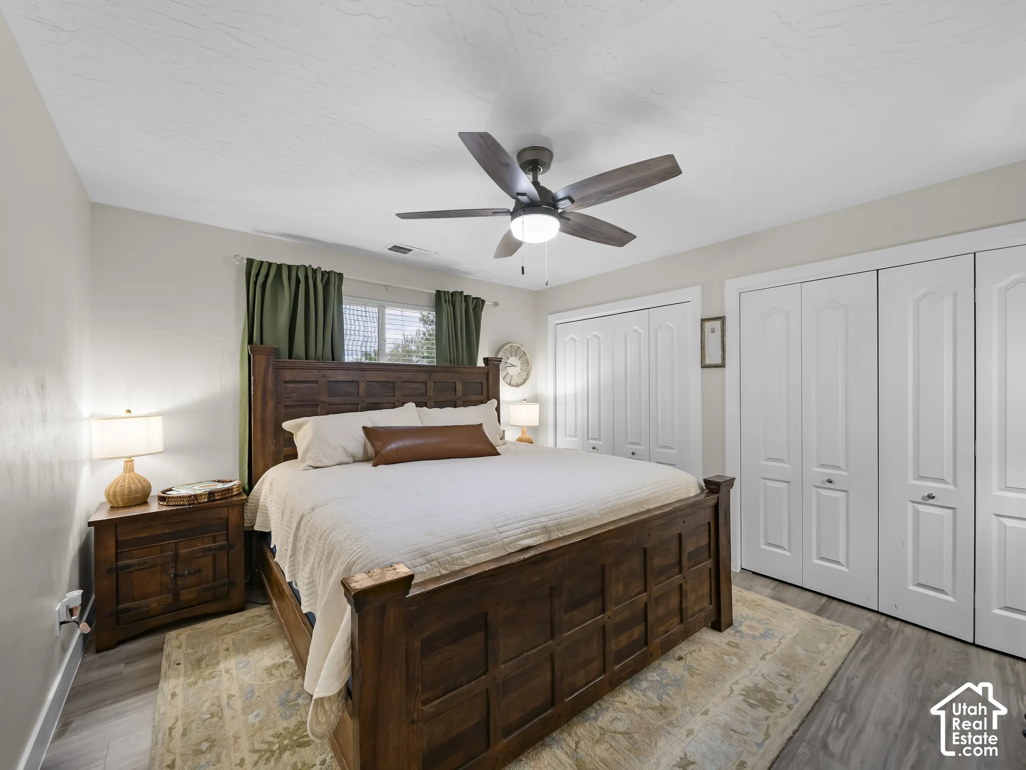Wood-finish flooring, ceiling fan with integrated lighting, and multiple paneled bi-fold closets