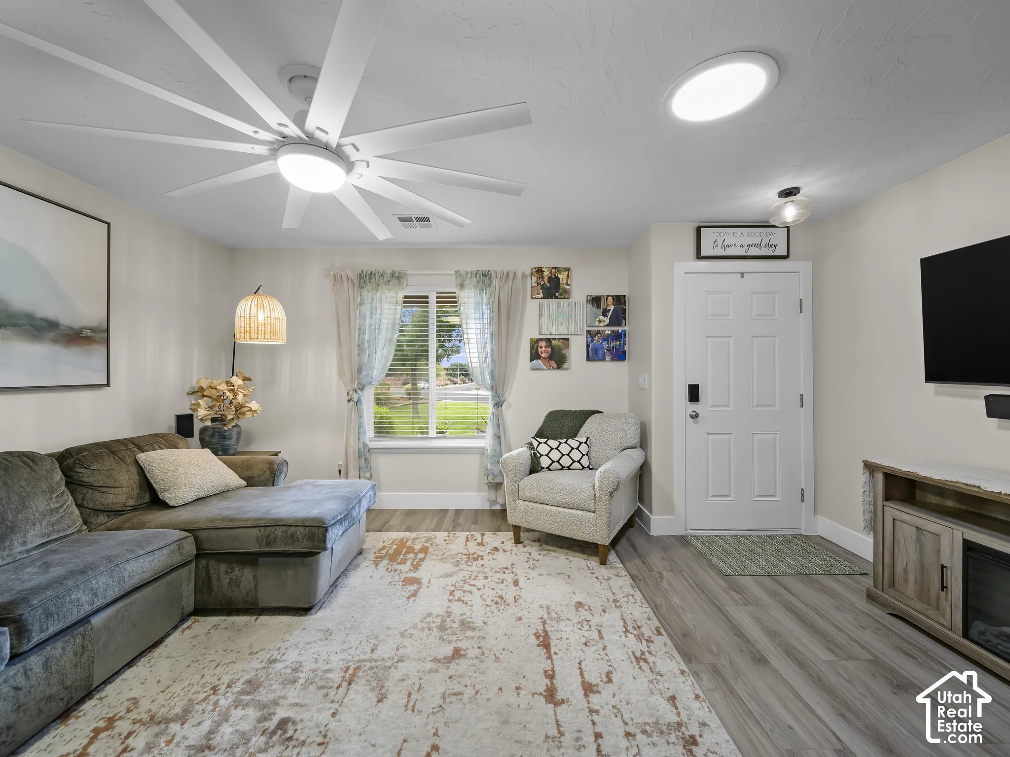 Recessed ceiling lighting, ceiling fan with integrated lighting, wood-finish flooring, paneled entry door, and built-in media console