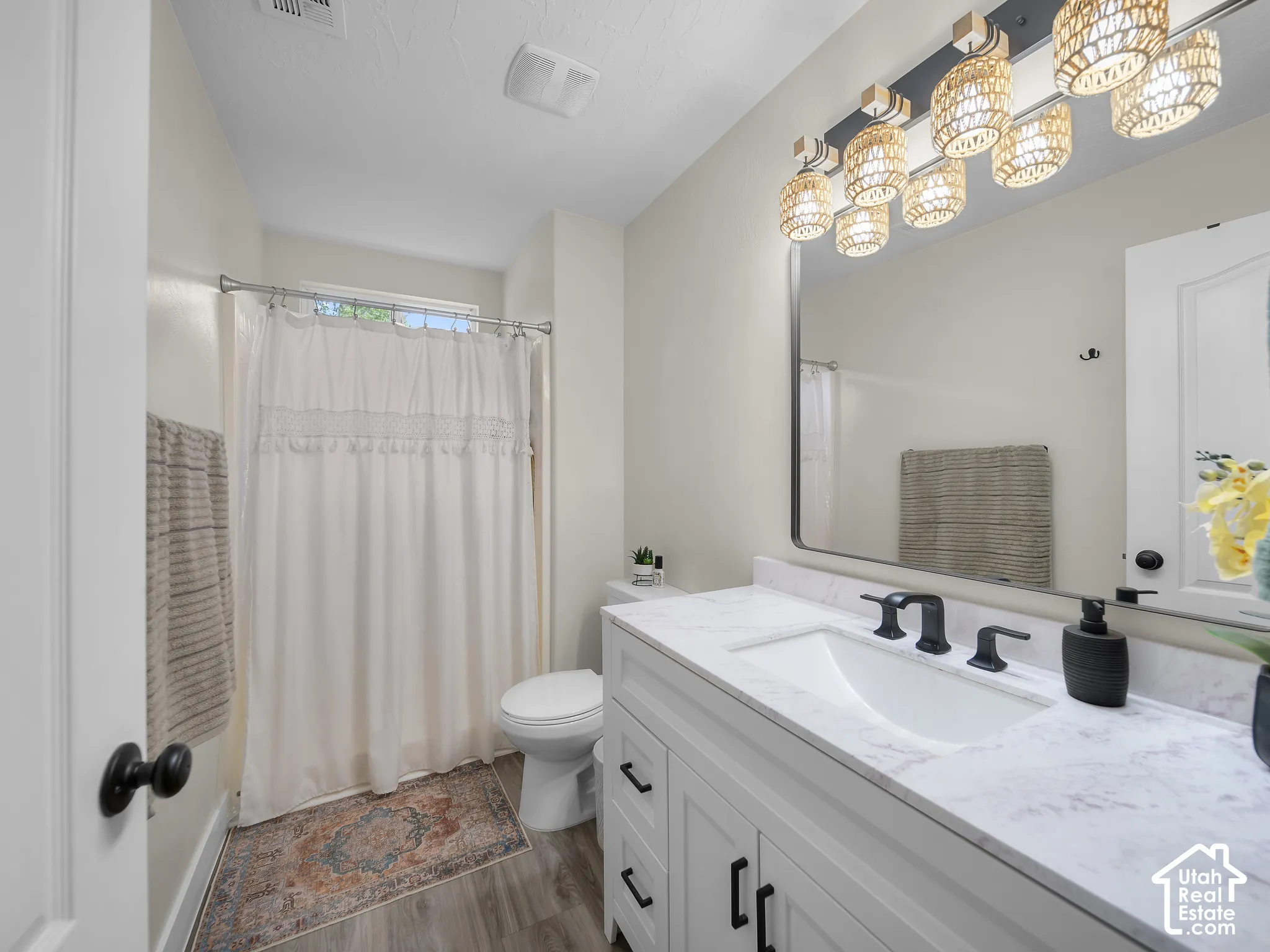 White vanity with matte black hardware, white countertop, rectangular undermount sink, and matte black faucet