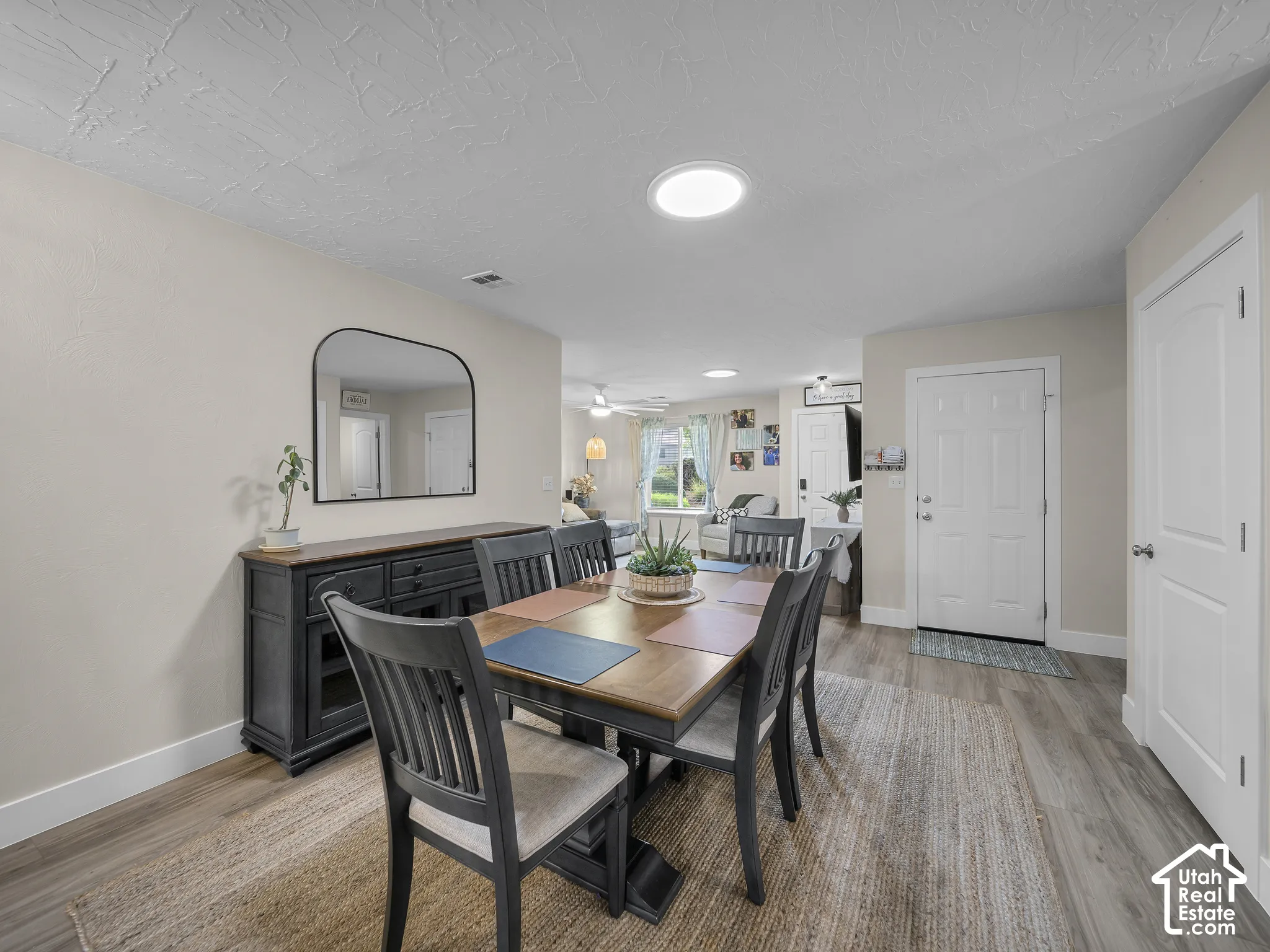 Recessed ceiling lighting, wood-finish flooring, and light neutral wall colors define this dining area