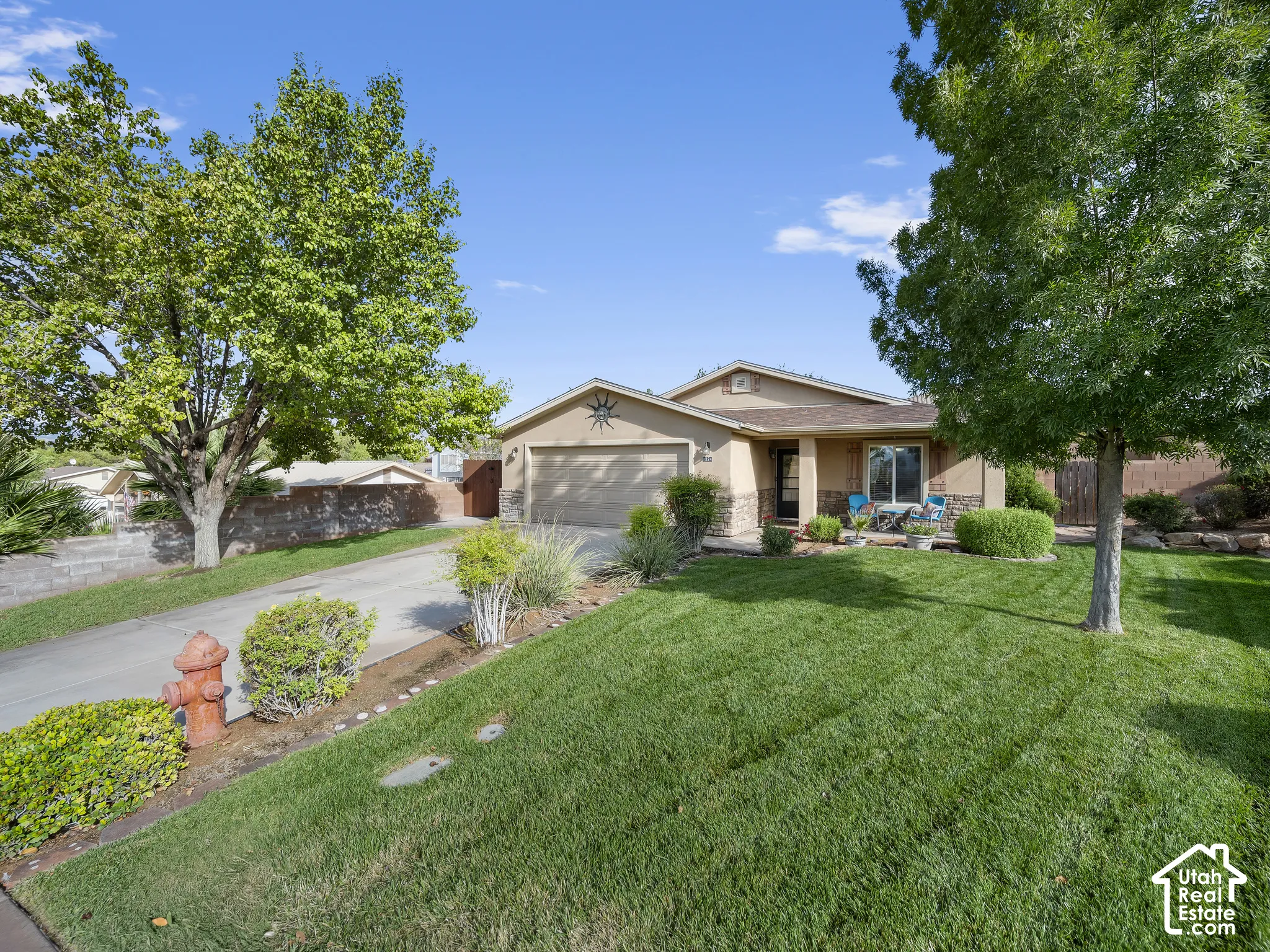 Expansive front lawn, mature trees, attached garage, stone accents on the facade, covered front entry
