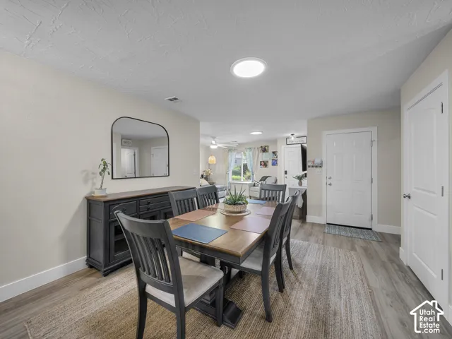 Recessed ceiling lighting, wood-finish flooring, and light neutral wall colors define this dining area