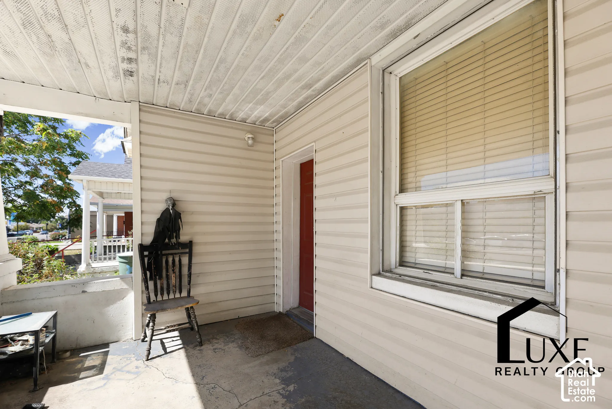 Porch with concrete flooring, cream-colored siding.