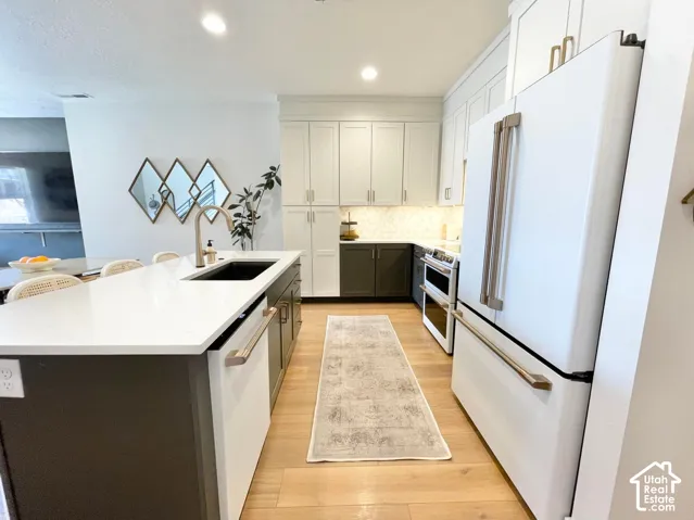 Kitchen with white countertops, wood-finish flooring, two-tone cabinetry, and integrated appliances