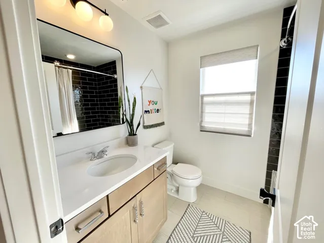 Vanity with a white countertop and undermount sink, light wood-finish cabinetry, black rectangular mirror, and three-light vanity fixture