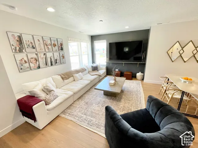 Open-concept living area featuring wood-finish flooring, recessed lighting, and a neutral color palette