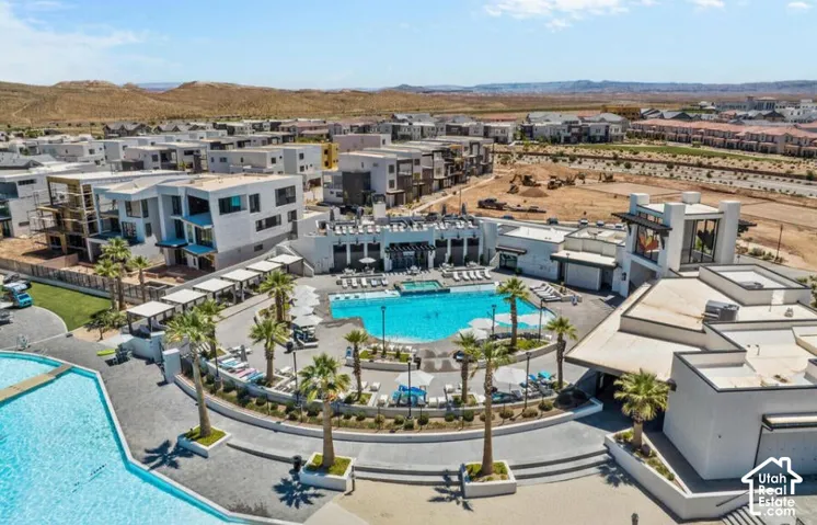 Resort-style pool with surrounding lounge areas, multiple mature palm trees, and modern architecture