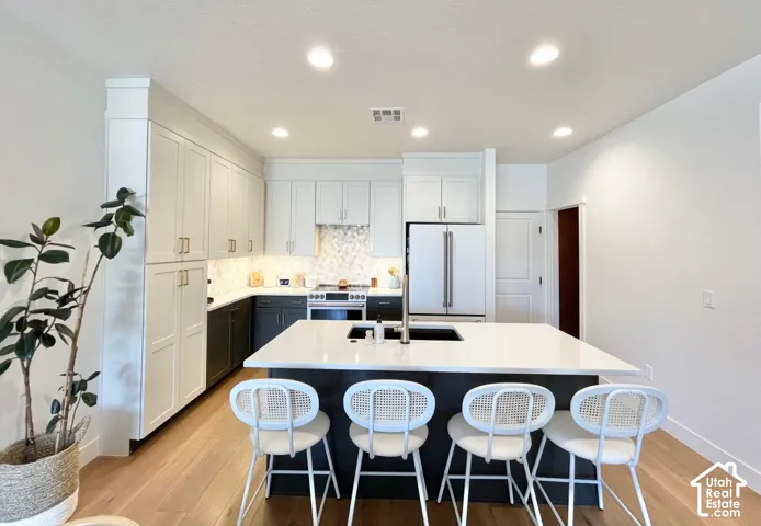 Modern kitchen featuring light wood-finish flooring, white upper cabinetry, and dark lower cabinetry