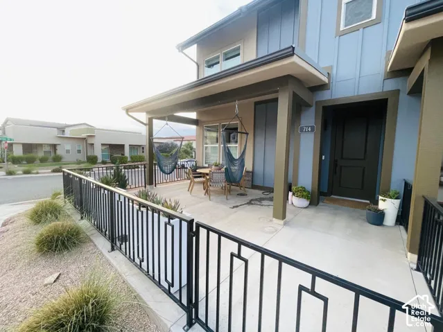 Covered front porch with concrete flooring and dark metal railings