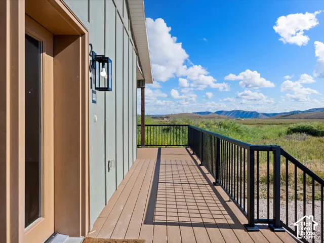 Expansive exterior decking with durable composite material, black metal railings, and a wall-mounted outdoor light fixture