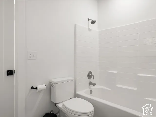 Tub and shower combination with white subway tile surround, chrome fixtures, and a dual-flush toilet