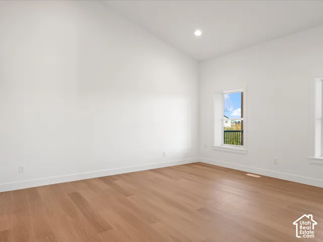 Vaulted ceilings, recessed lighting, wood-finish flooring, white trim, and bright windows