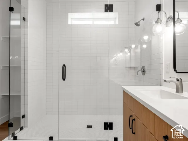 Glass-enclosed shower with white subway tile, a shower niche, and a contrasting black hardware