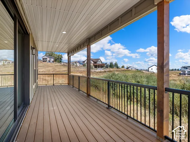 Expansive covered deck featuring wood-finish flooring, recessed lighting, and black metal railing