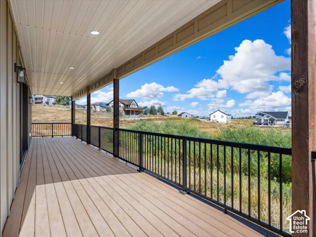 Expansive covered deck featuring composite decking, recessed lighting, and black metal railings