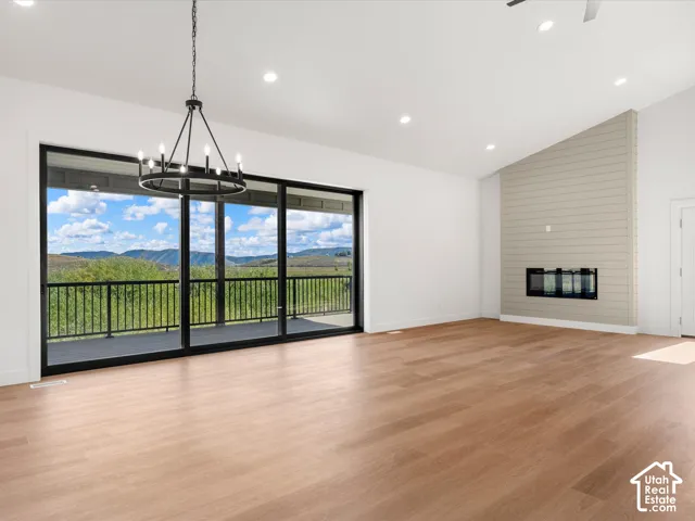 Expansive wood-finish flooring, a contemporary fireplace with shiplap surround, and a large sliding glass door opening to a balcony with black metal railing