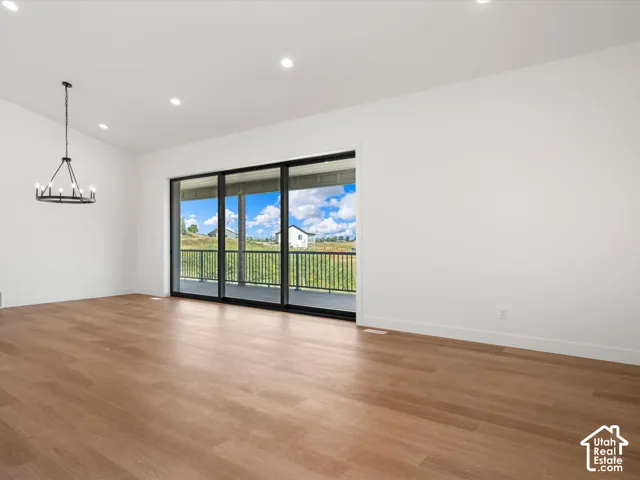Vaulted ceilings with recessed lighting, wood-finish flooring, a black-framed multi-panel sliding glass door, and a black metal chandelier