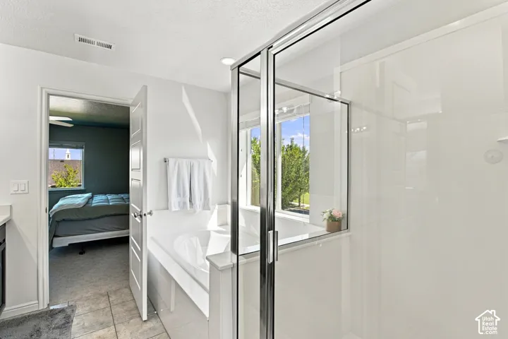 Glass-enclosed shower with sliding door, built-in bathtub, and window with outdoor scenery
