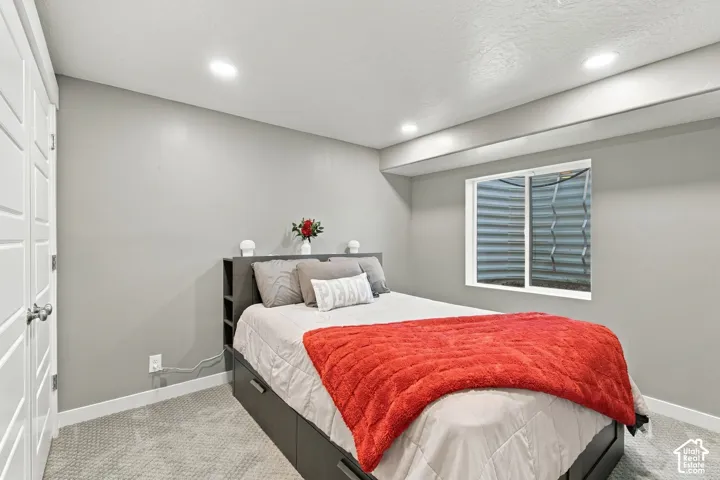 Recessed ceiling lighting, light gray wall finishes, light gray carpet, white trim, and a window with a window well