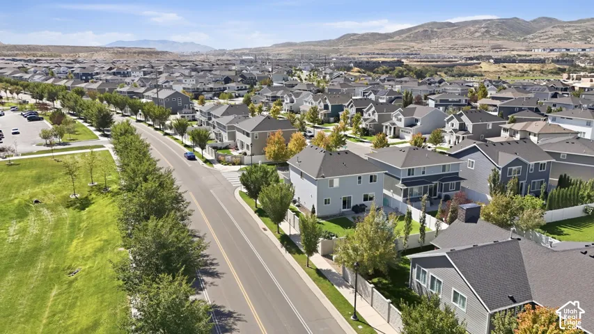Expansive residential development with a mountain backdrop, featuring varied architectural styles, asphalt streets, and mature landscaping