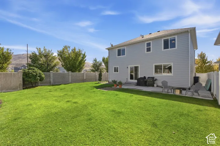 Expansive backyard with a manicured lawn, concrete patio, and a concrete perimeter fence
