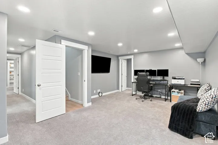 Recessed lighting and light gray walls complement the gray carpeting