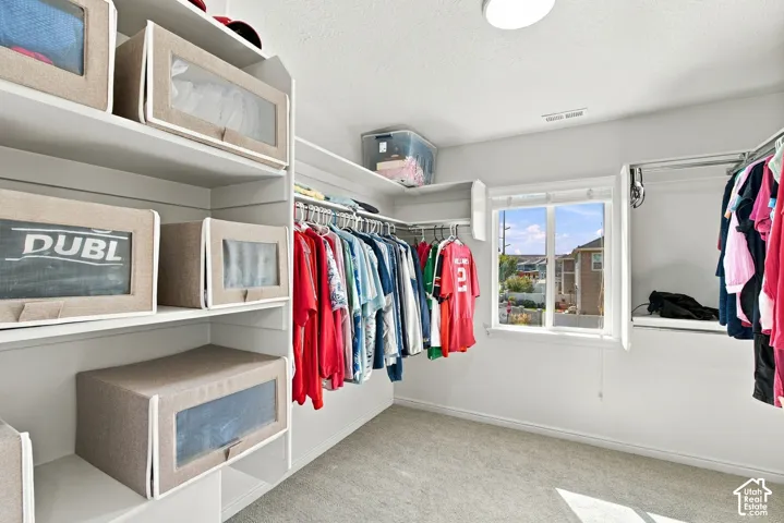 Walk-in closet featuring extensive built-in shelving, multiple hanging rods, a window, and recessed lighting