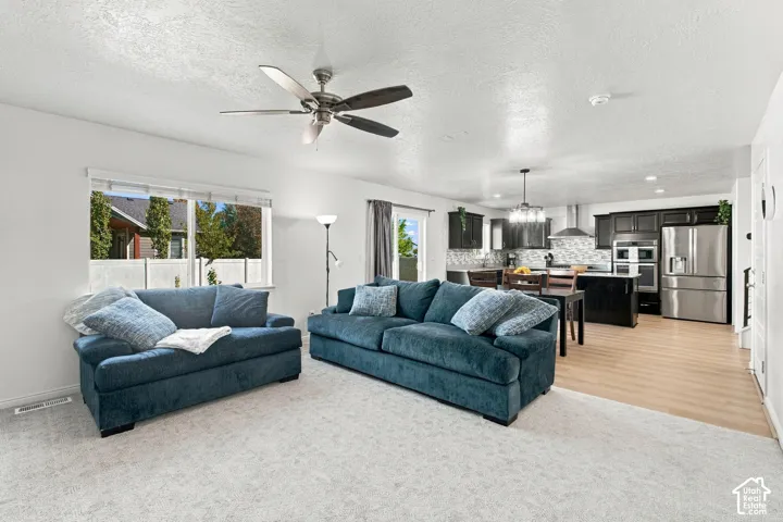 Open-concept living area with light-toned carpeting and wood-finish flooring