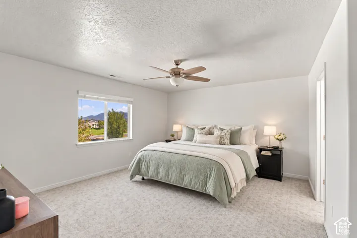 Virtually staged. Spacious room featuring neutral carpeting, a dual-pane window, and a ceiling fan with light fixture