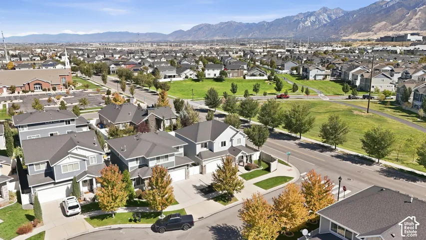 Residential neighborhood featuring detached homes with varied architectural styles, mature trees, green spaces, and a mountainous backdrop