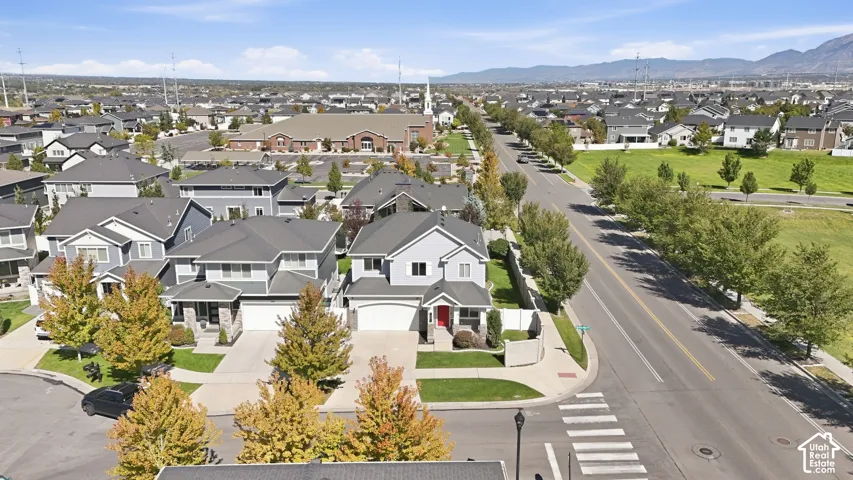 Residential neighborhood with mature trees, paved streets, and mountain backdrop