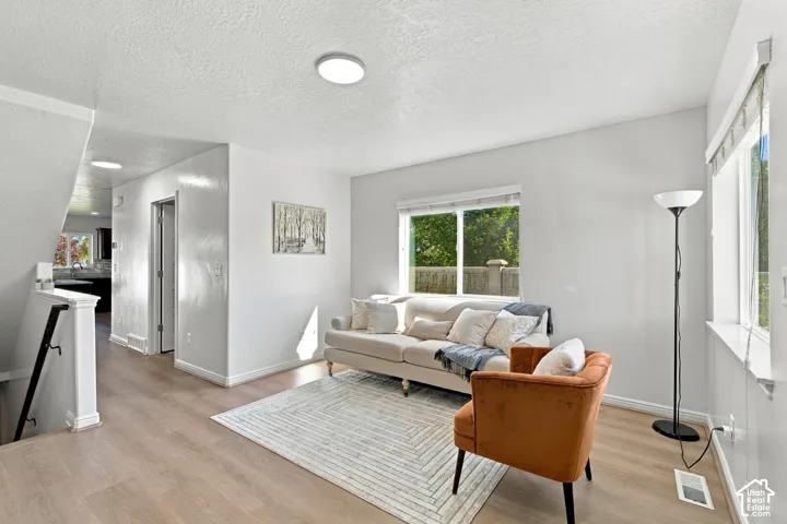 Recessed lighting, wood-finish flooring, white walls, multiple windows, and a staircase with a white railing