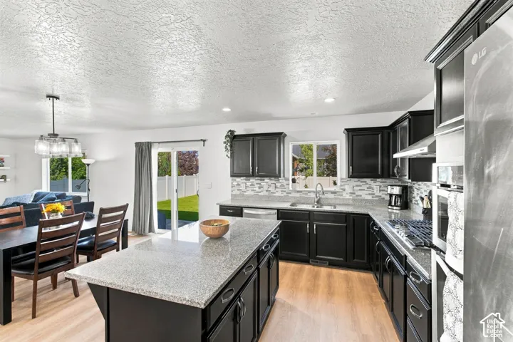 Kitchen featuring dark wood cabinetry, light-toned countertops, a tile backsplash, and stainless steel appliances