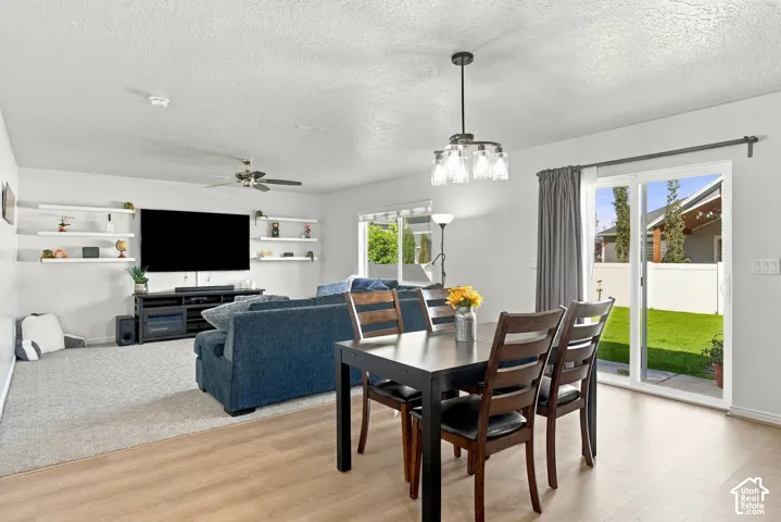 Open-concept living space with a ceiling fan, a contemporary chandelier, and wood-finish flooring