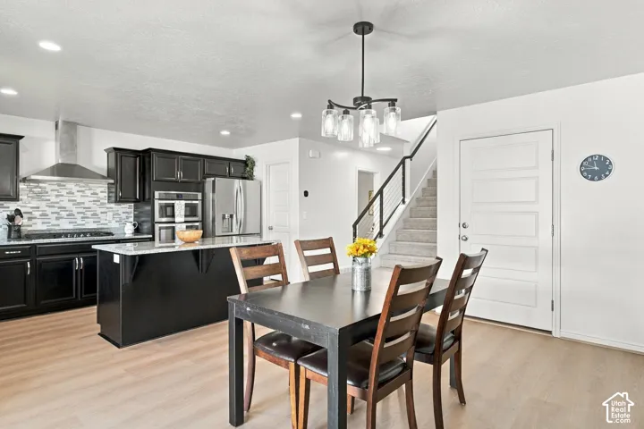 Modern kitchen with dark cabinetry, stainless steel appliances, and a tiled backsplash
