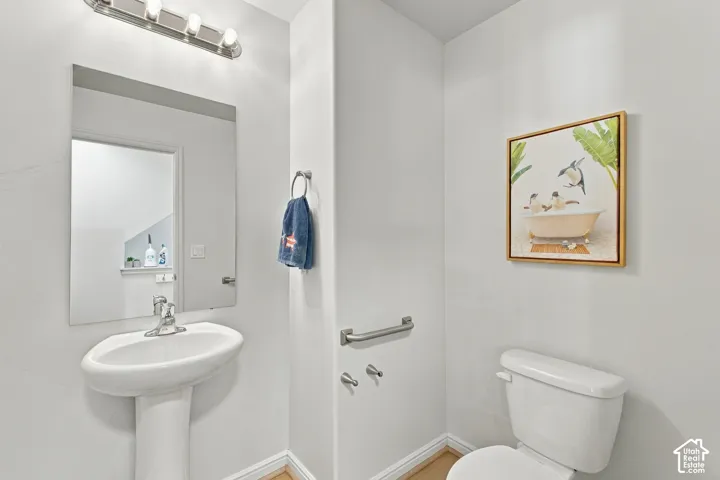 Pedestal sink with chrome faucet, wall-mounted mirror, and overhead vanity lighting
