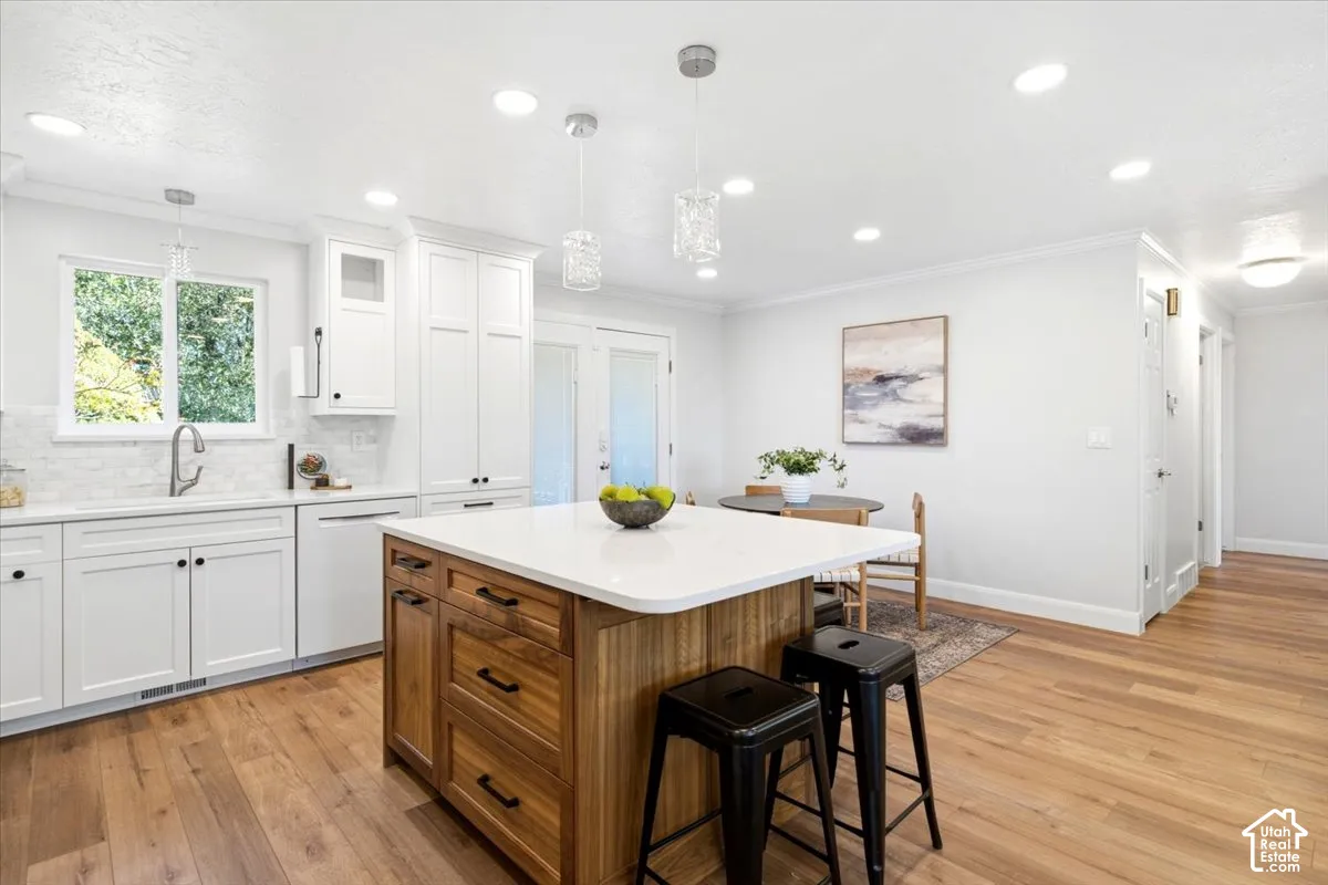 Kitchen with wood-finish flooring, white cabinetry, a white countertop island with wood-finish base, and recessed lighting