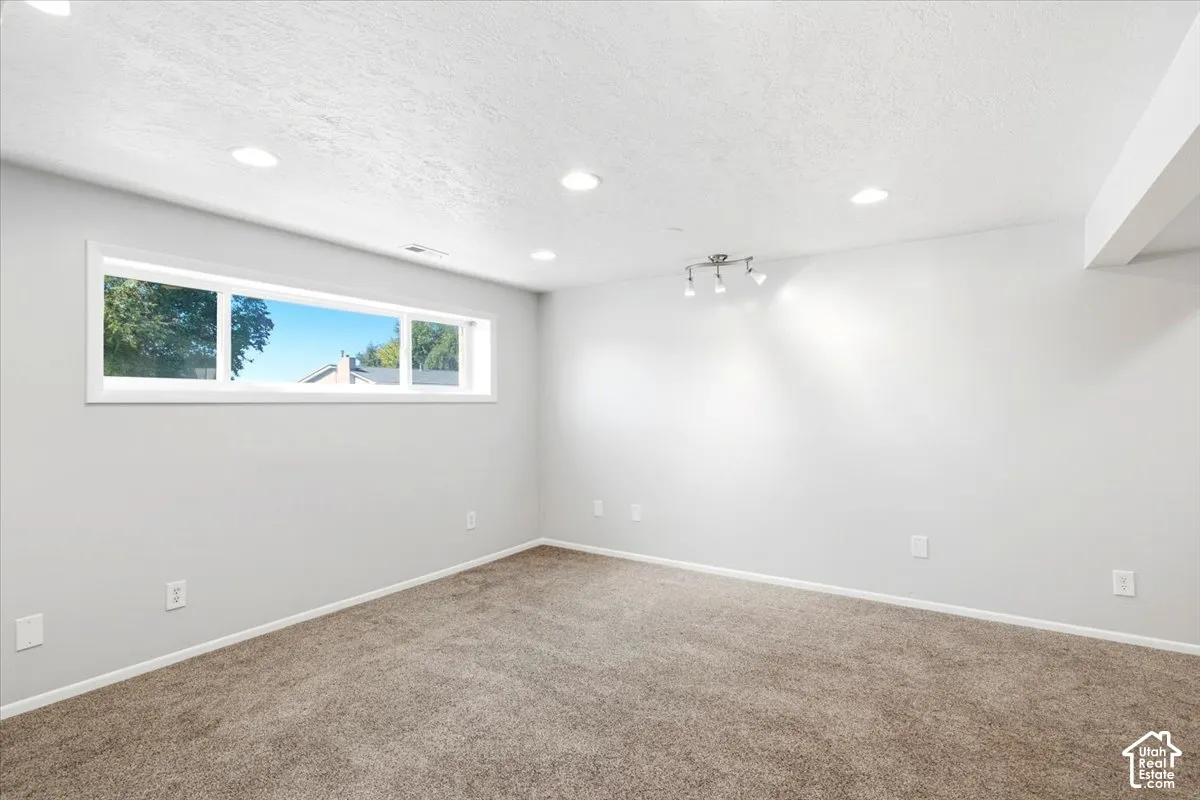 Wall-to-wall carpeting with light gray walls, recessed ceiling lighting, and a white-framed window