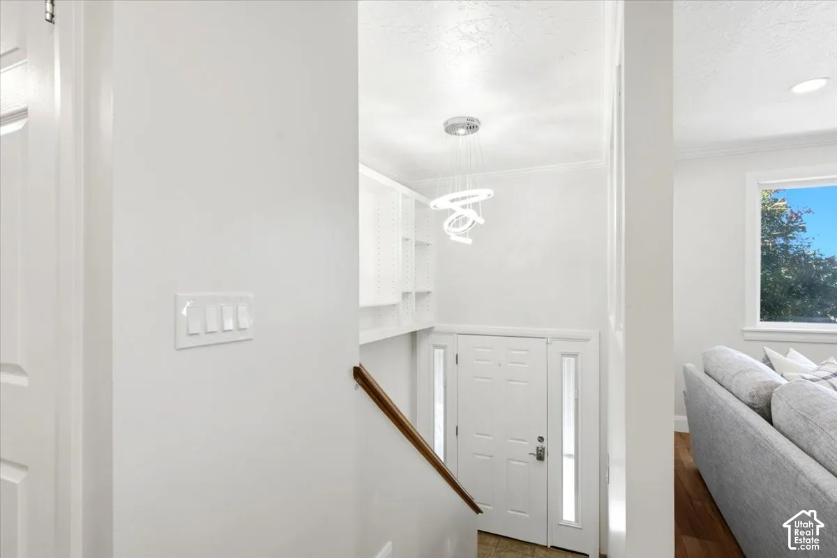 Bright entry foyer with a modern chandelier, built-in shelving, and wood flooring