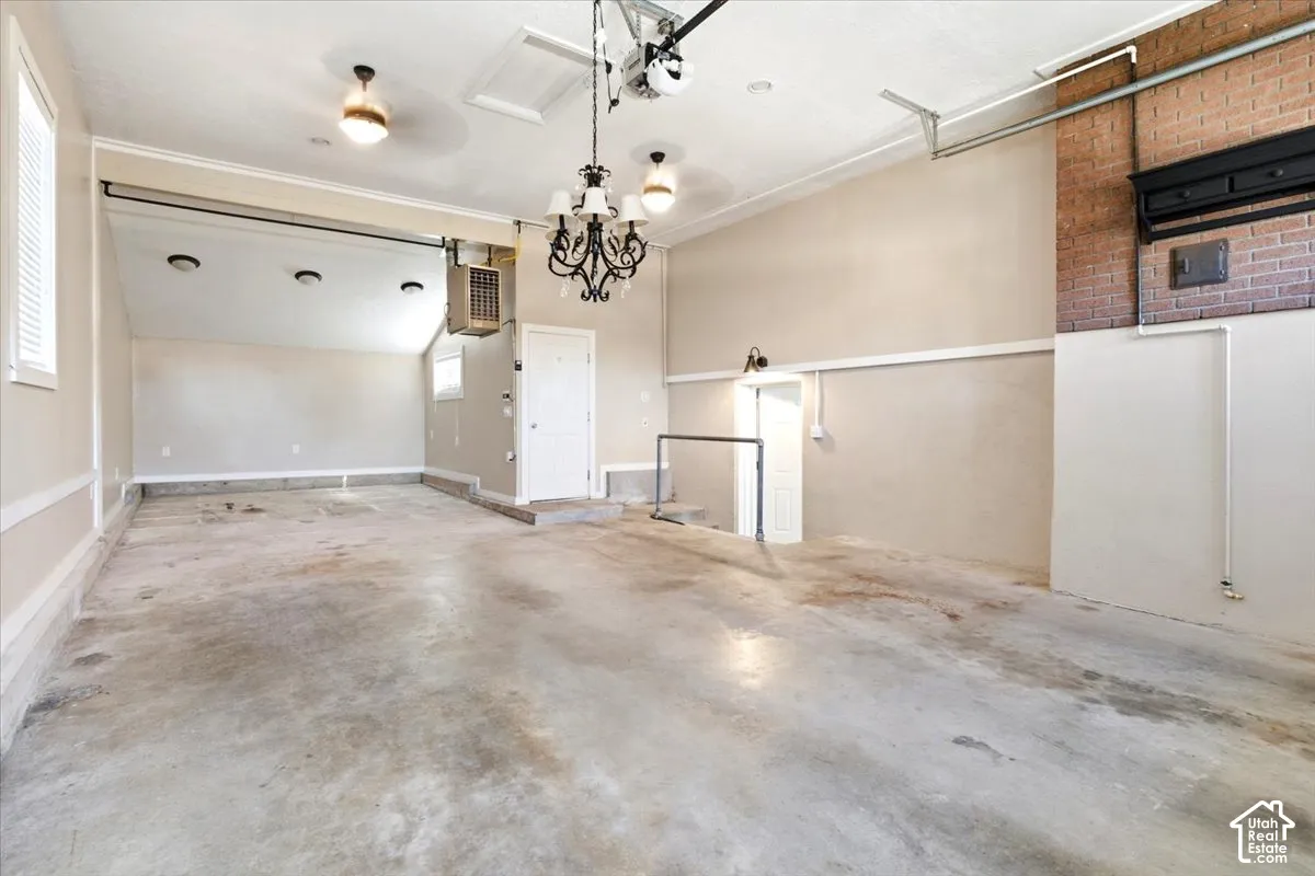 Expansive concrete flooring, white trim details, multiple windows, exposed brick accent wall, and decorative lighting fixtures
