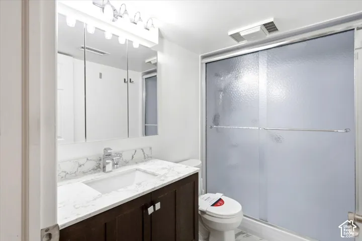 Dark wood-finish vanity with a white rectangular undermount sink, a chrome-finish faucet, and a light-toned countertop