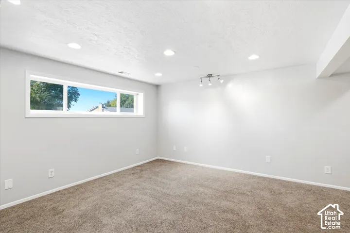 Wall-to-wall carpeting with light gray walls, recessed ceiling lighting, and a white-framed window
