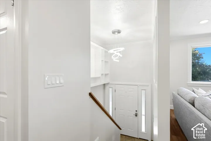 Bright entry foyer with a modern chandelier, built-in shelving, and wood flooring