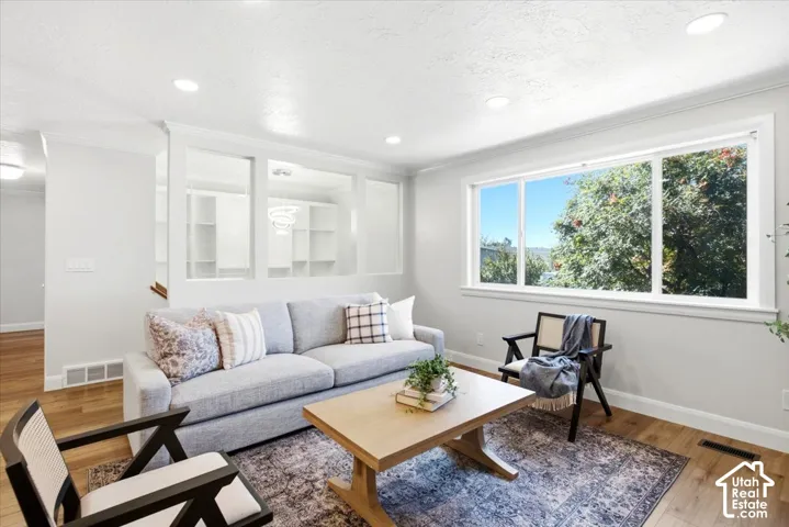 Recessed ceiling lighting, wood-finish flooring, white trim, and a large multi-pane window