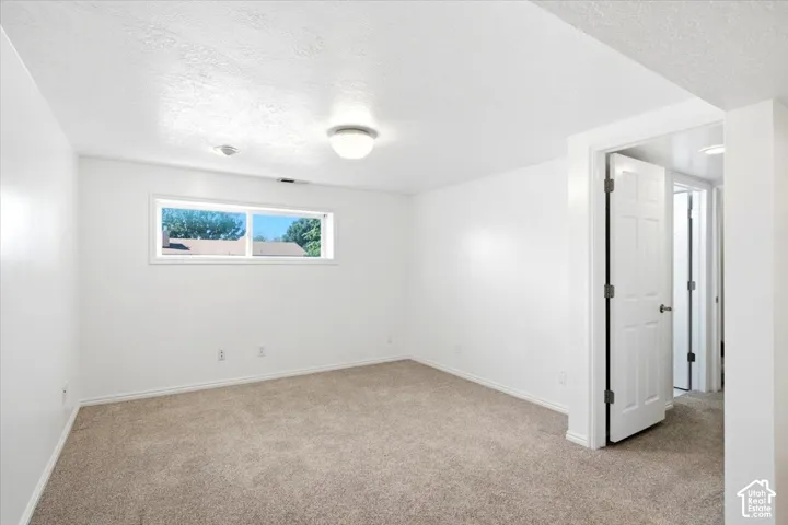 Neutral-toned carpet flooring, white painted walls, and a single window with a white frame