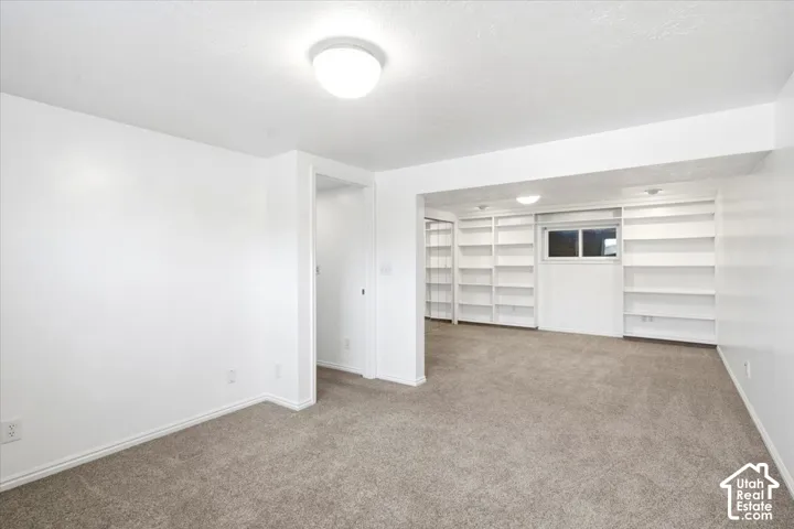 Recessed ceiling lighting, built-in shelving, window, and neutral carpeting