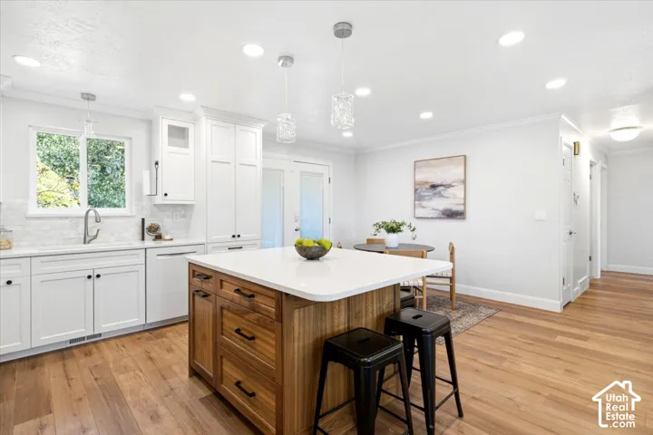 Kitchen with wood-finish flooring, white cabinetry, a white countertop island with wood-finish base, and recessed lighting